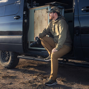 Man sitting inside a van in a desert landscape with mountains in the background